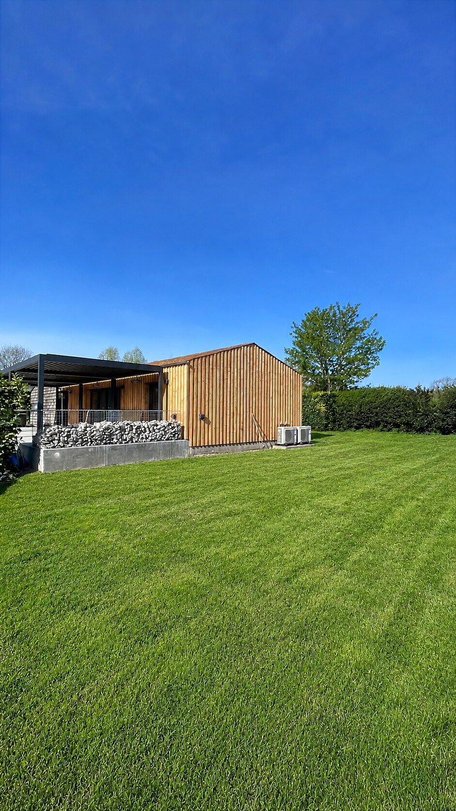 Finished exterior with larch cladding and gabion wall, The Birch Room